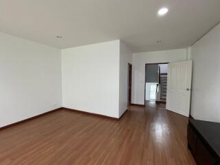 Spacious empty bedroom with wooden flooring and white walls