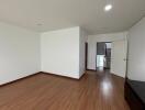 Spacious empty bedroom with wooden flooring and white walls