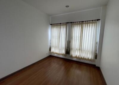 Empty bedroom with hardwood floor and curtained windows