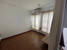 Bedroom with wooden floor and light curtains