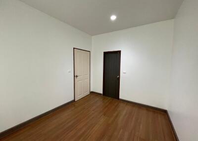 Empty bedroom with wooden floor and two doors