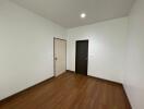 Empty bedroom with wooden floor and two doors