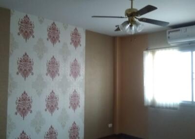 Bedroom with wooden flooring, a ceiling fan, a wallpapered accent wall, air conditioning unit, and a window with curtains