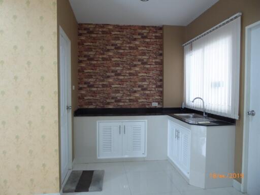 Small kitchen with brick backsplash and white cabinets