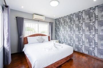 Bedroom with a double bed, patterned wallpaper, and air conditioning.