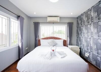 Well-lit bedroom with large bed, modern wallpaper, and air conditioner