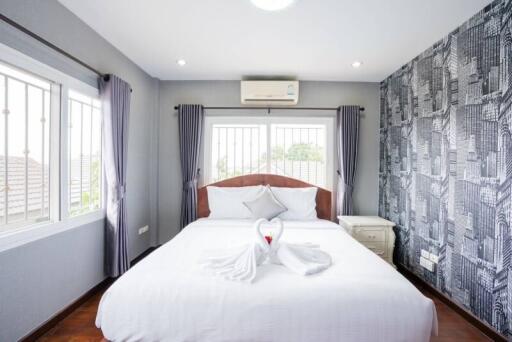 Well-lit bedroom with large bed, modern wallpaper, and air conditioner