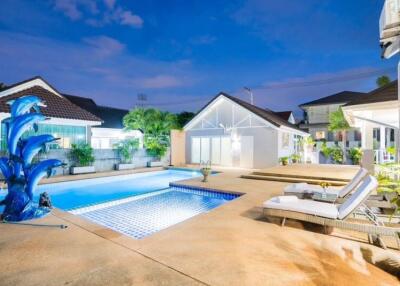 Beautiful outdoor area with a swimming pool and lounge chairs at dusk