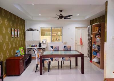 Dining area with a glass-topped table and chairs, adjacent to a storage shelf