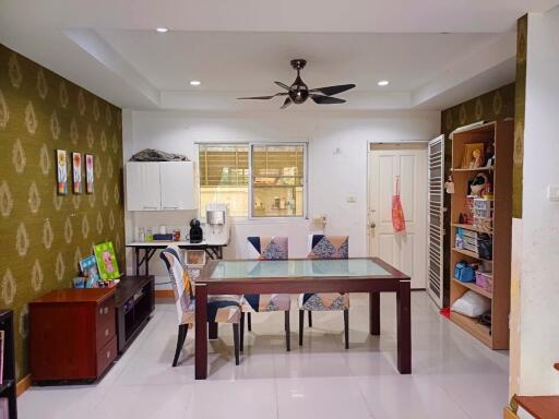 Dining area with a glass-topped table and chairs, adjacent to a storage shelf