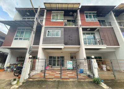 Front view of a multi-story residential building with gated entrance and multiple balconies