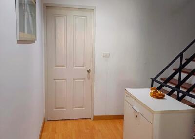 Hallway with wooden floor and white walls leading to a door