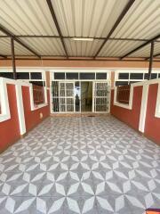 Spacious covered outdoor area with tiled flooring and gated entry