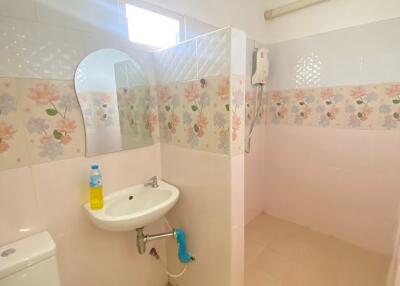 Small bathroom with floral wall tiles, sink, toilet, and water heater