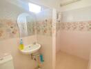 Small bathroom with floral wall tiles, sink, toilet, and water heater