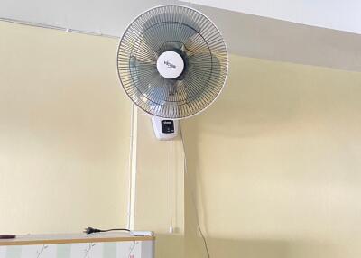 Wall-mounted fan in a room with fridge