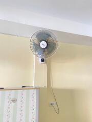 Wall-mounted fan in a room with fridge