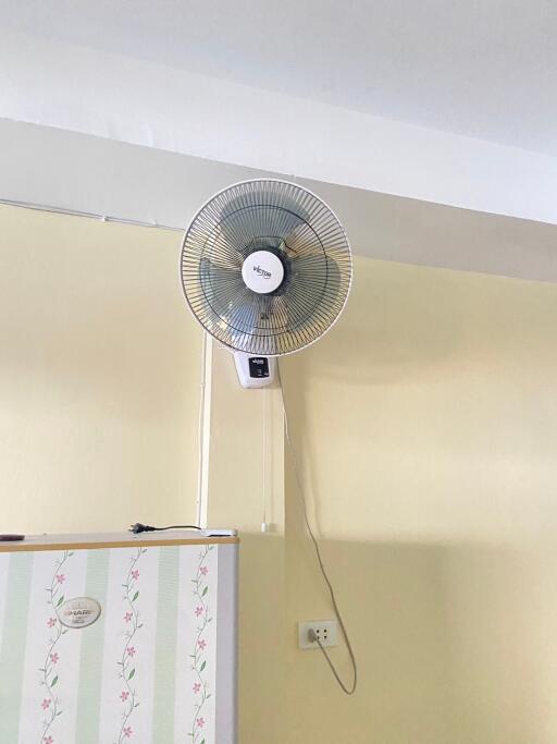 Wall-mounted fan in a room with fridge