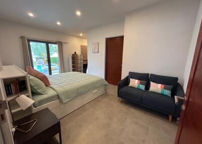 Bedroom with a pool view, featuring a bed, sofa, and bookshelf.