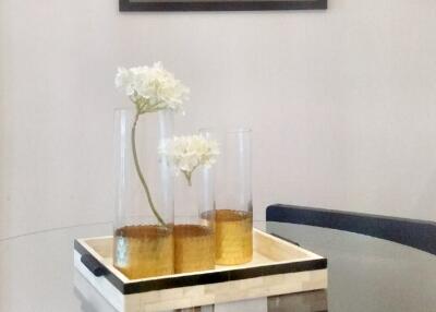 Glass dining table with decorative flowers and framed art on the wall