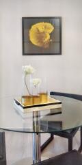 Glass dining table with decorative flowers and framed art on the wall