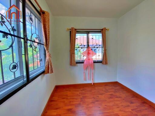 Bright bedroom with wooden flooring and patterned window grills