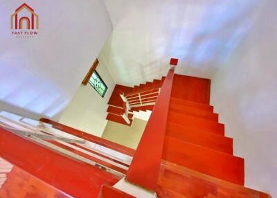 View of a red staircase with wooden steps and white railings