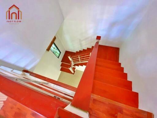 View of a red staircase with wooden steps and white railings