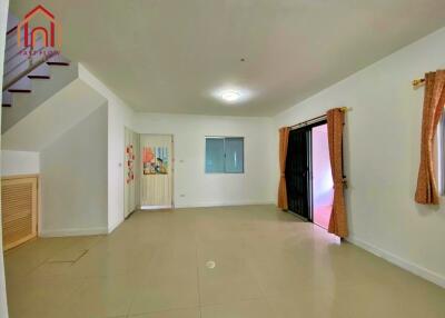 Spacious living room with tiled flooring, large window, and adjacent staircase