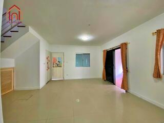 Spacious living room with tiled flooring, large window, and adjacent staircase