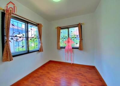 Bright bedroom with wooden flooring and dual windows