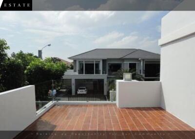 Spacious balcony with a clear view of a modern house and lush green surroundings