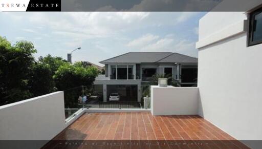 Spacious balcony with a clear view of a modern house and lush green surroundings