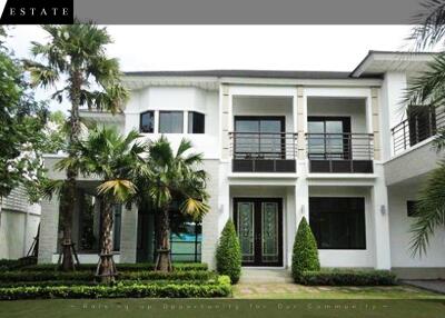 Modern two-story house exterior with palm trees and manicured lawn