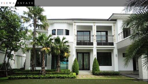 Modern two-story house exterior with palm trees and manicured lawn