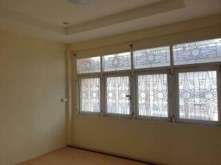 A well-lit bedroom with large windows and decorative grills