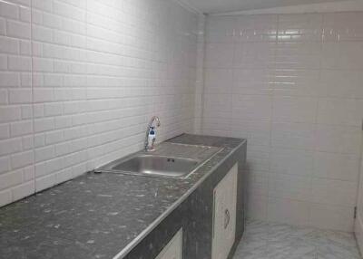 Clean, modern kitchen with marble countertop and white tiled backsplash.