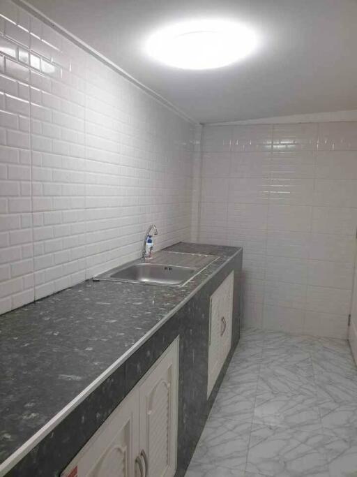 Clean, modern kitchen with marble countertop and white tiled backsplash.