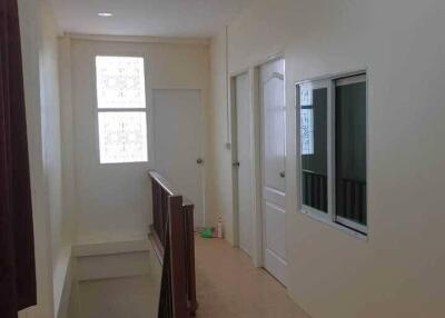 Well-lit hallway with cream-colored walls and wooden handrails