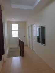 Well-lit hallway with cream-colored walls and wooden handrails