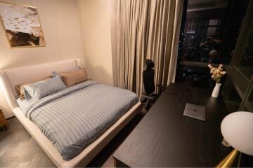 Bedroom with bed, desk, chair and night view through window