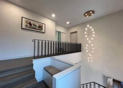 Staircase landing with modern chandelier and wall art