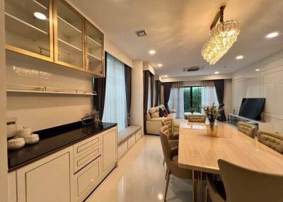 Modern dining area and living space with elegant chandelier and ample natural light