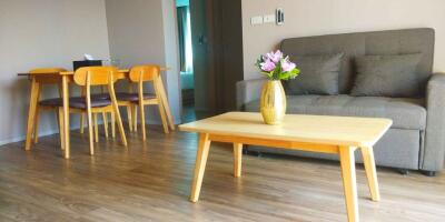 Living room with a grey sofa, wooden coffee table, and dining set