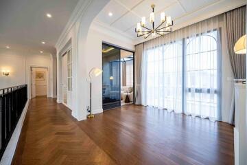 Spacious living room with hardwood floors, chandelier, and large windows