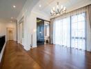 Spacious living room with hardwood floors, chandelier, and large windows