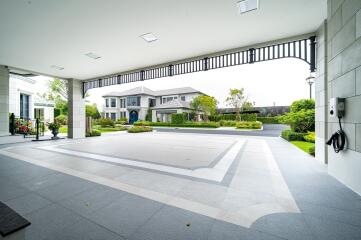 View of a spacious and modern house exterior with a large driveway and landscaped garden