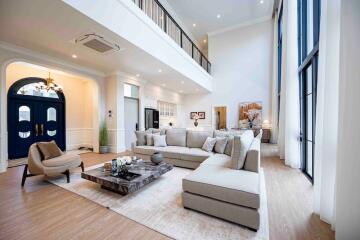 Spacious living room with high ceiling, modern furniture, and large windows