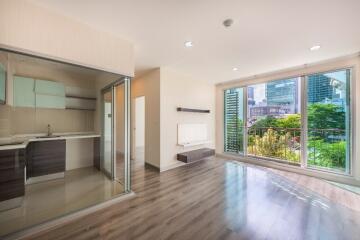 Modern open-plan living room with large windows and adjacent kitchen