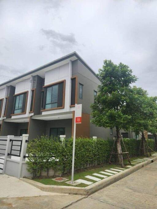 Exterior view of a modern two-story townhouse with greenery